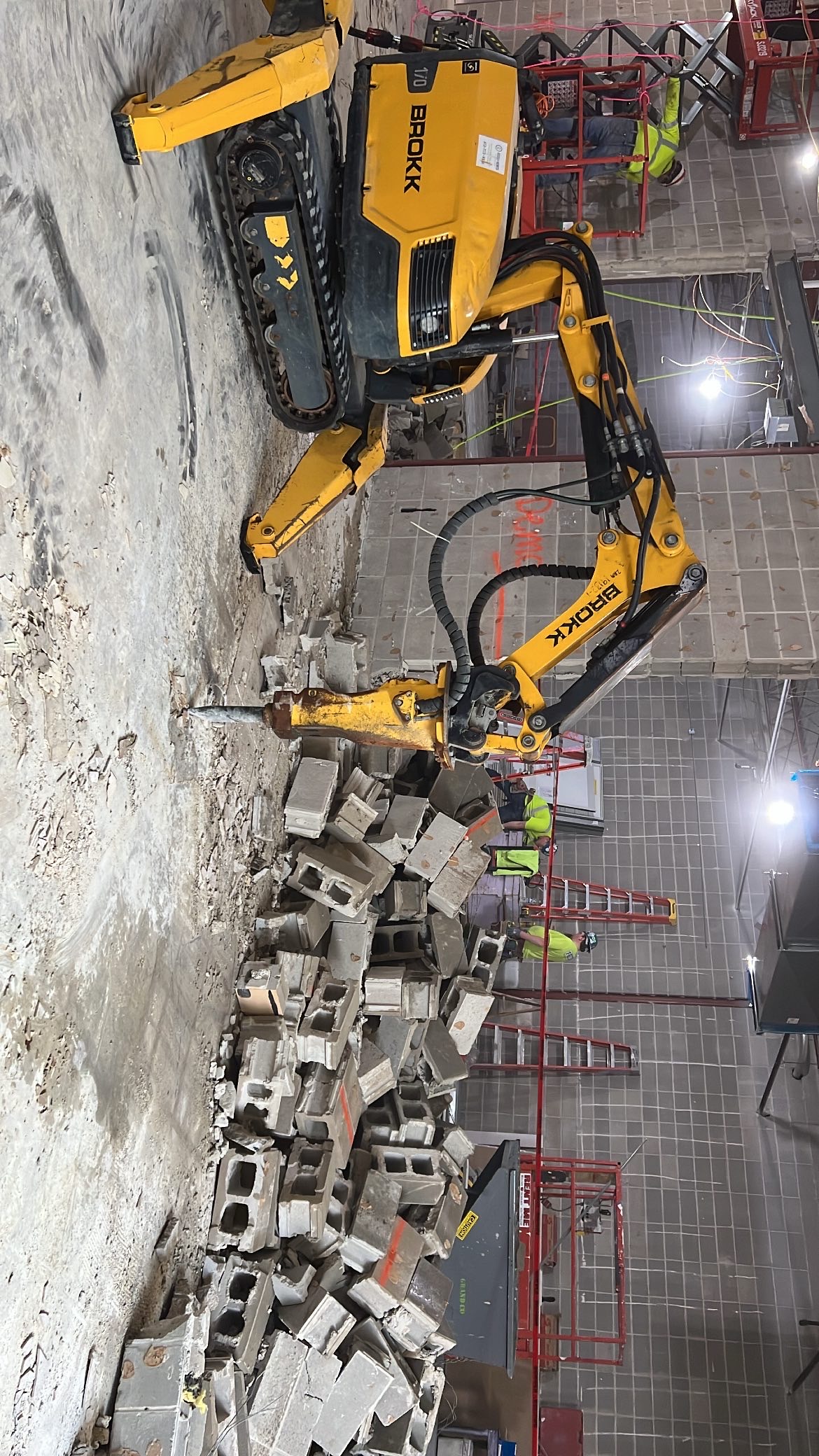 Remote-controlled robotic demolition machine breaking concrete indoors