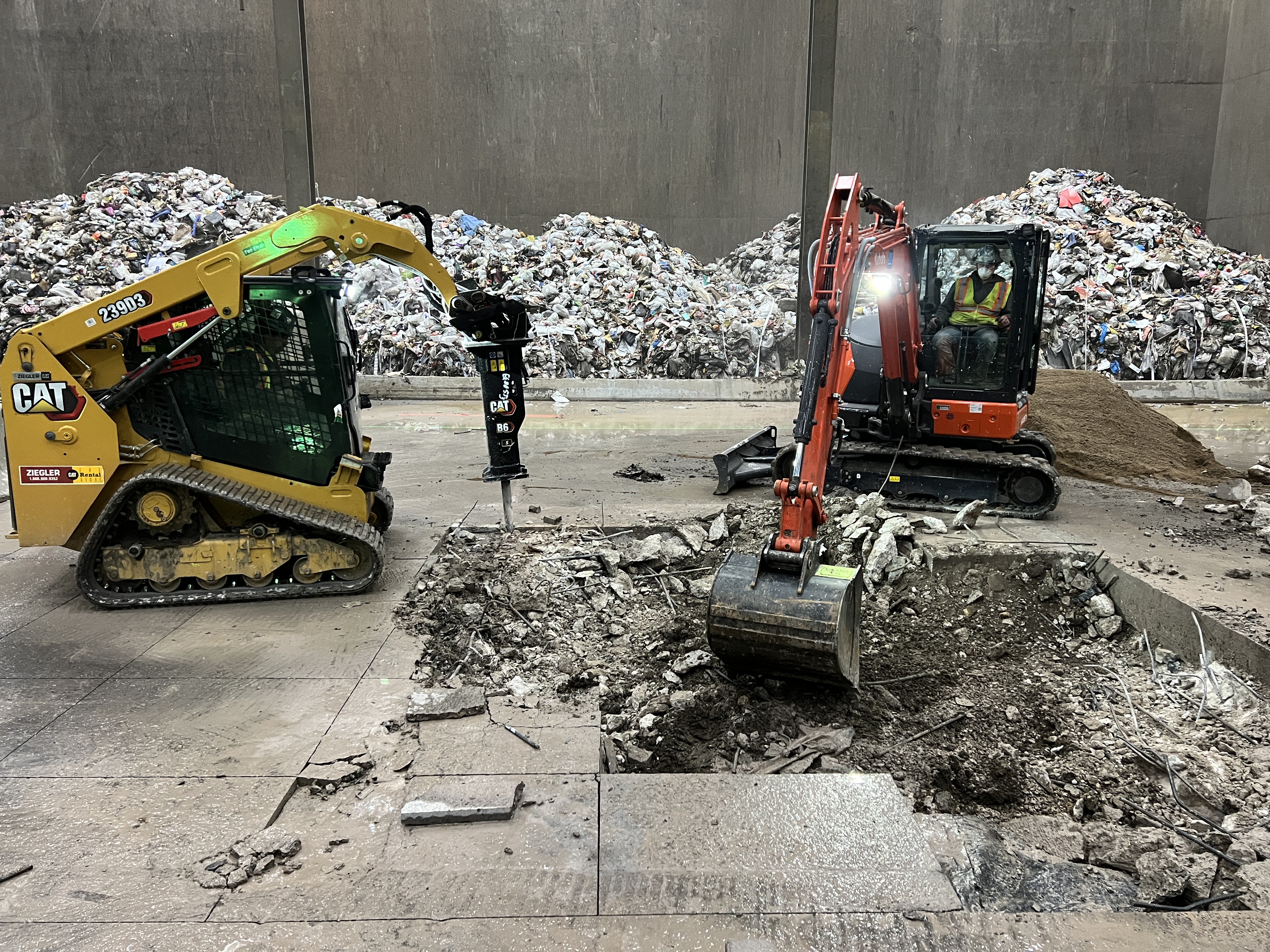Excavator removing broken concrete from a demolition site