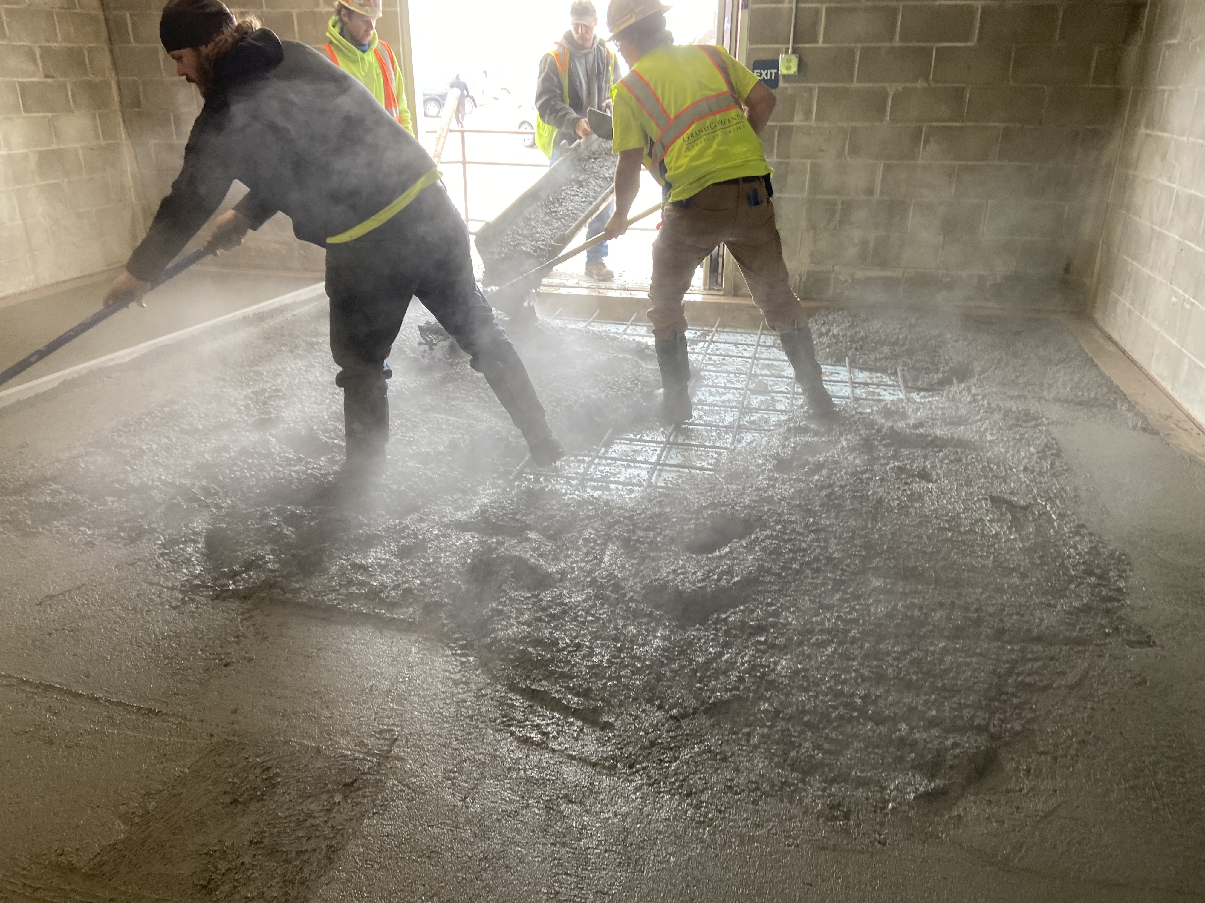Fresh concrete being placed and finished on an interior pad